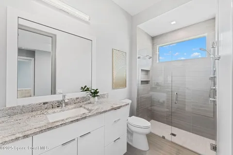 a bathroom with a granite countertop sink a toilet and shower