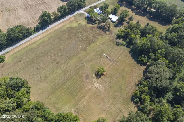 an aerial view of a residential houses with outdoor space and trees