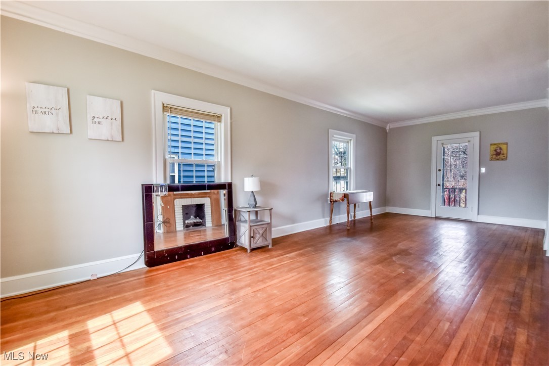 3733 East Antisdale Road Cleveland, OH 44118 - Photo 6 of 28 Unfurnished living room featuring baseboards, ornamental molding, and wood-type flooring