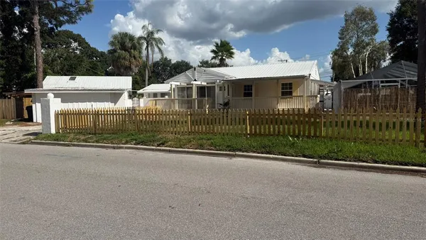 a view of a house with a small yard and large trees
