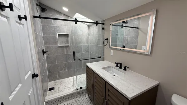 a bathroom with a shower sink and mirror