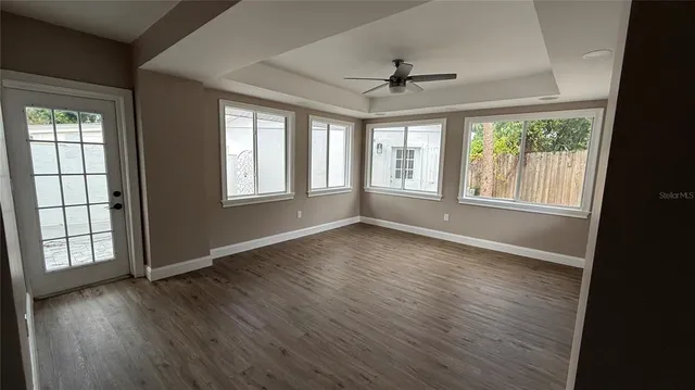 a view of an empty room with wooden floor and a window