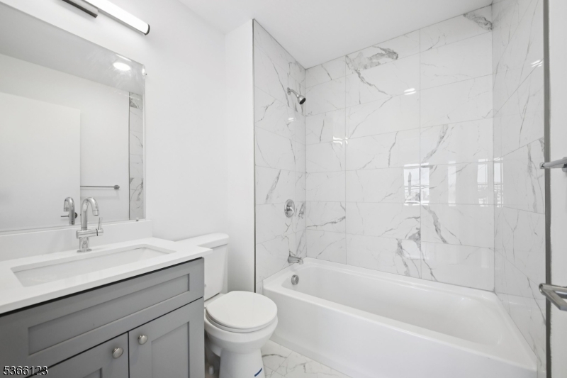 369 18th Avenue, Unit 304 Newark, NJ 07108 - Photo 9 of 18 a bathroom with a bathtub shower sink vanity mirror and toilet