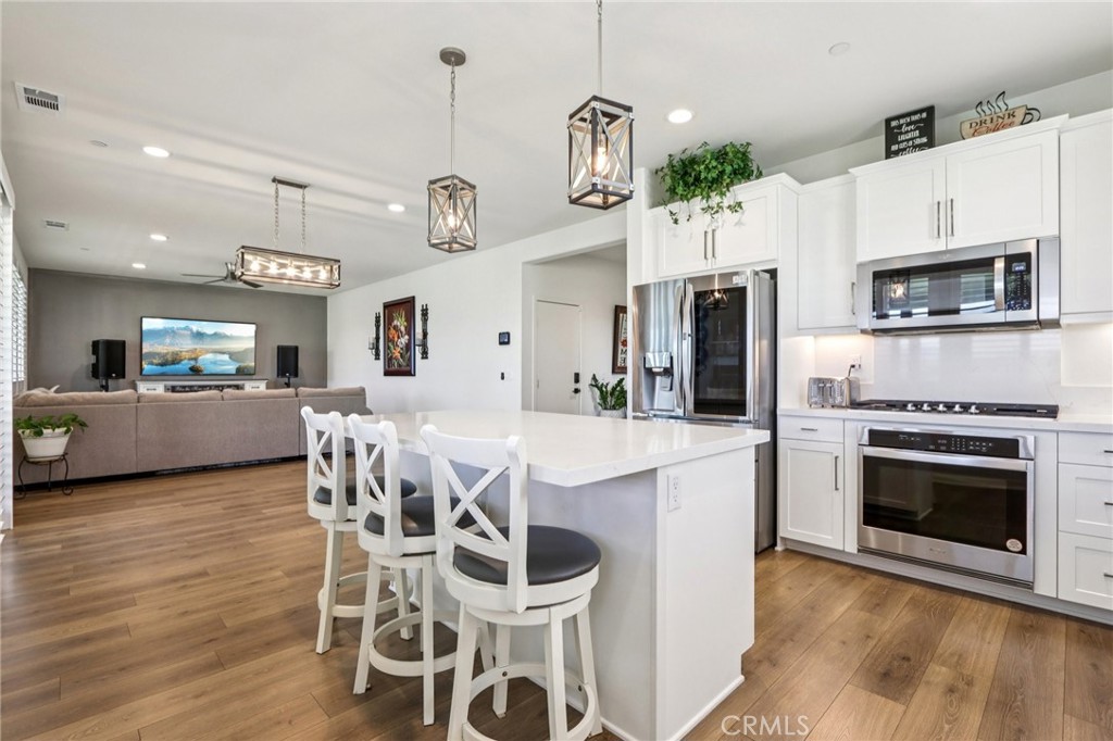 35293 Funk Way Beaumont, CA 92223 - Photo 16 of 70 a kitchen with stainless steel appliances kitchen island granite countertop a stove a microwave a oven a dining table and chairs with wooden floor