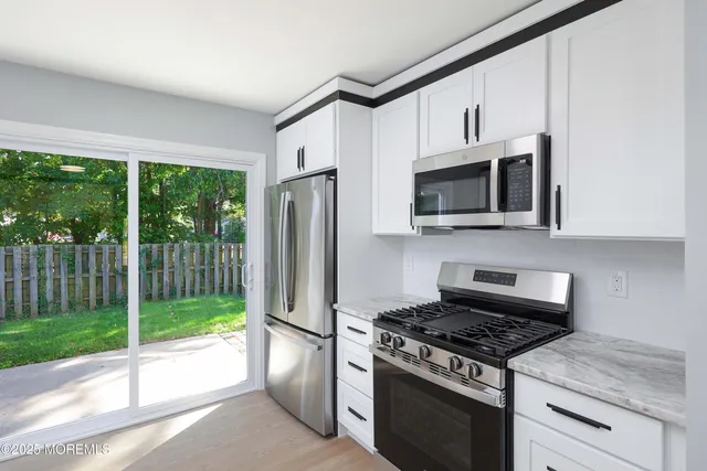 a kitchen with stainless steel appliances granite countertop a stove a refrigerator and a microwave