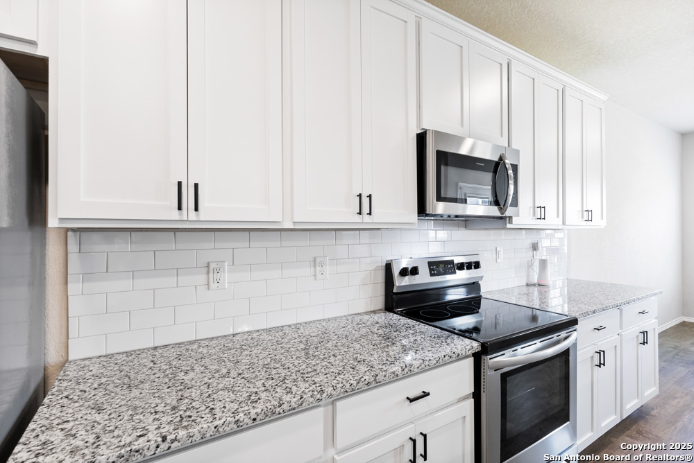 19916 Doc Holiday Drive Lytle, TX 78052 - Photo 12 of 27 a kitchen with stainless steel appliances granite countertop a sink stove and microwave