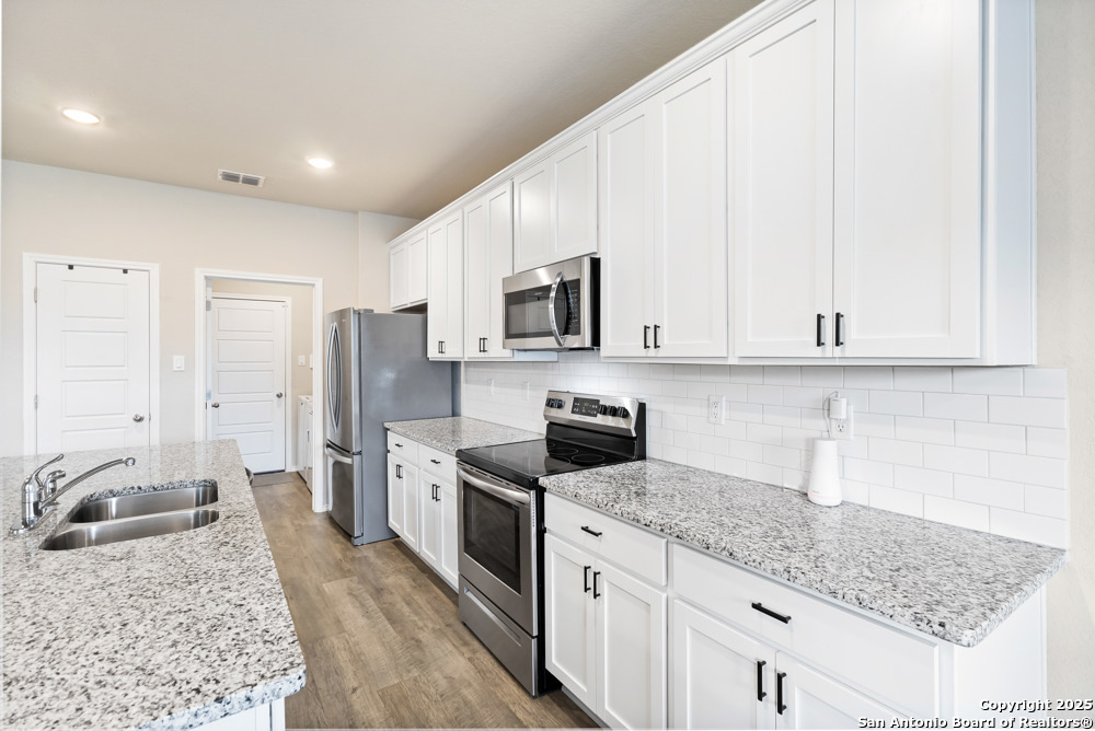 19916 Doc Holiday Drive Lytle, TX 78052 - Photo 9 of 27 a kitchen with stainless steel appliances granite countertop a sink stove and refrigerator