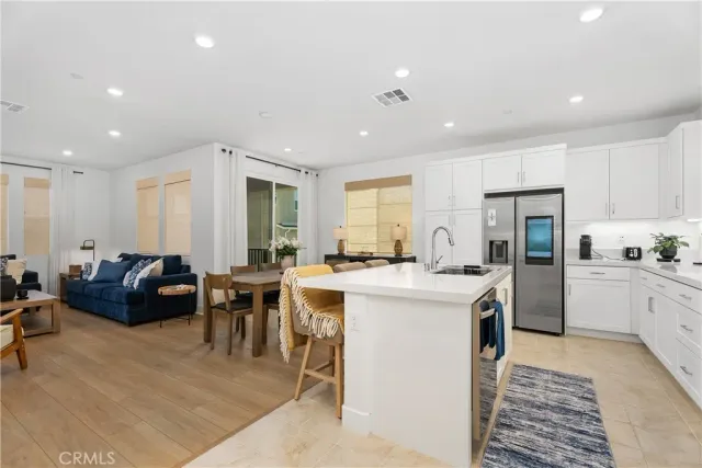 a kitchen that has a lot of cabinets a sink a stove and chairs in it