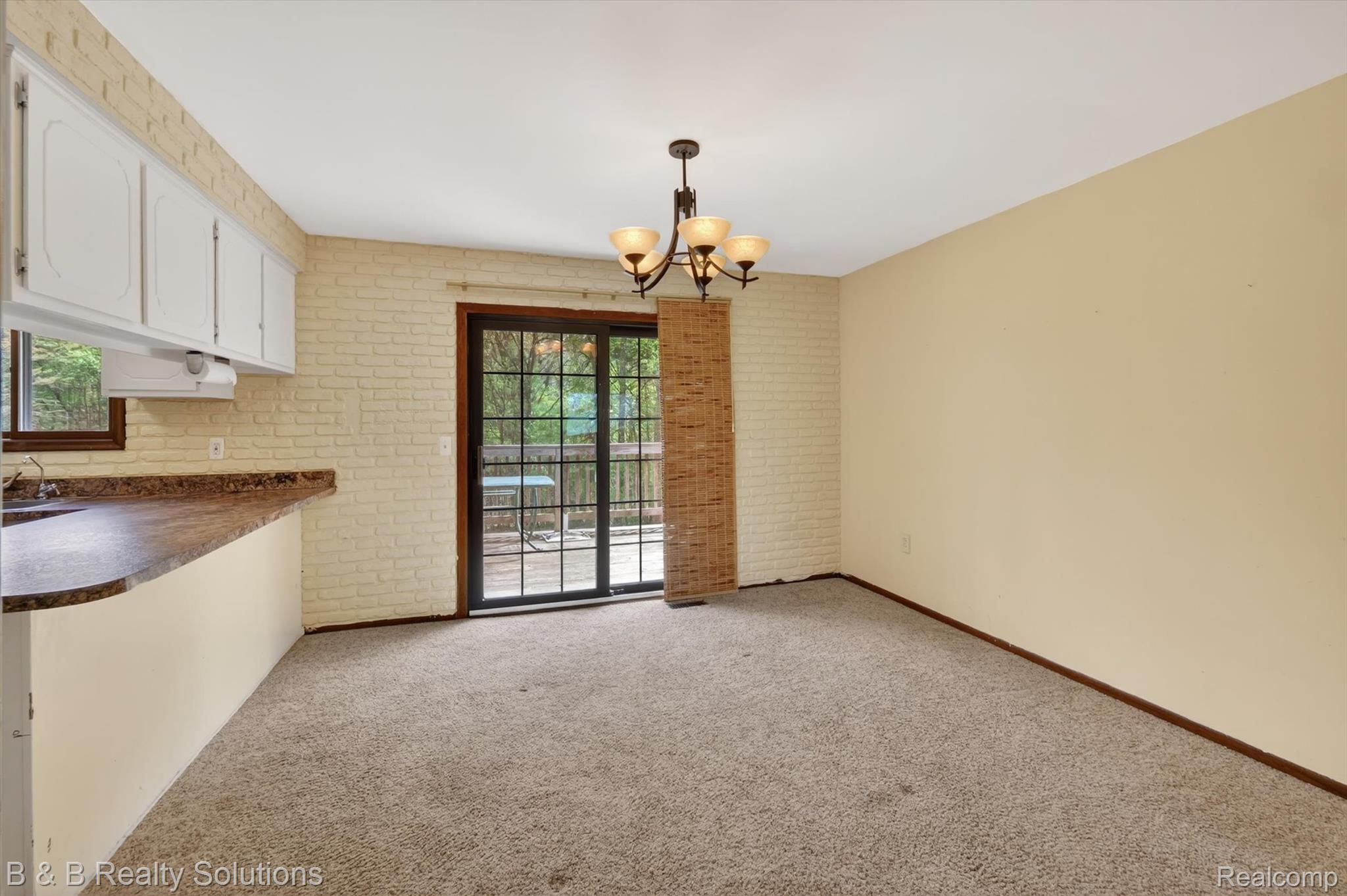 2467 North Lake George Road Metamora, MI 48455 - Photo 8 of 46 Unfurnished dining area with light carpet, brick wall, and a chandelier
