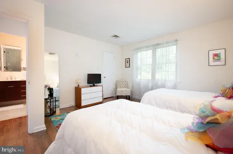 a bedroom with a large bed and a flat tv screen on dresser