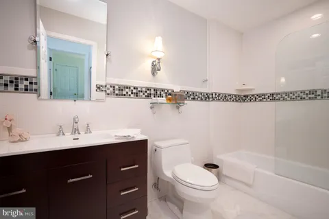 a bathroom with a sink a toilet a mirror a bathtub and shower