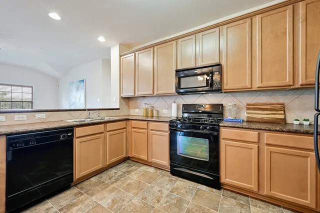 a kitchen with granite countertop a stove top oven microwave and cabinets