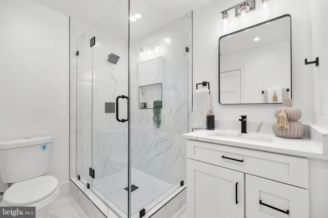 a bathroom with a granite countertop sink a toilet and shower