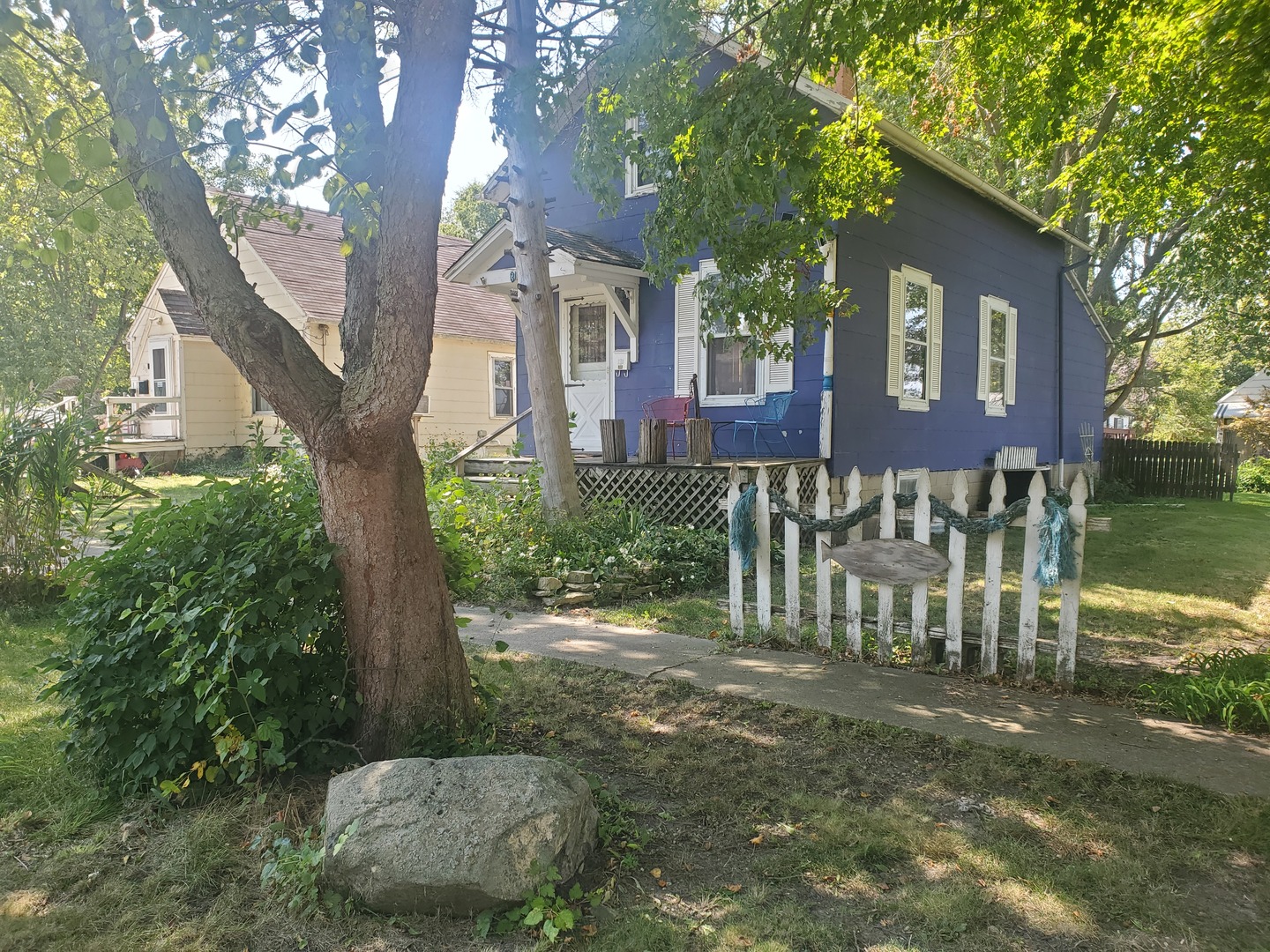 a view of a brick house with a yard plants and large tree