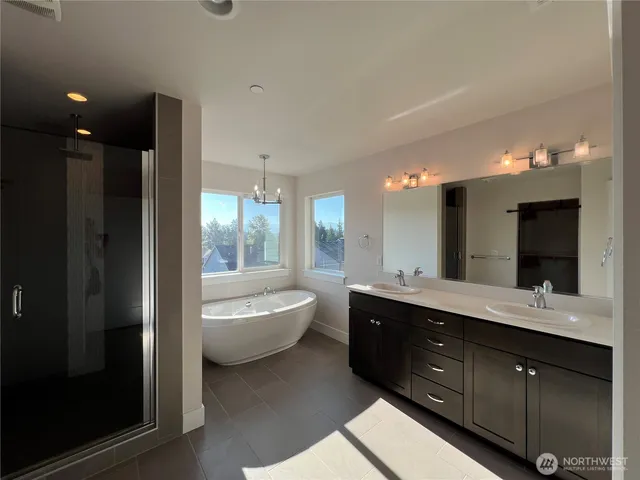 a spacious bathroom with a double vanity sink a large mirror and a bathtub