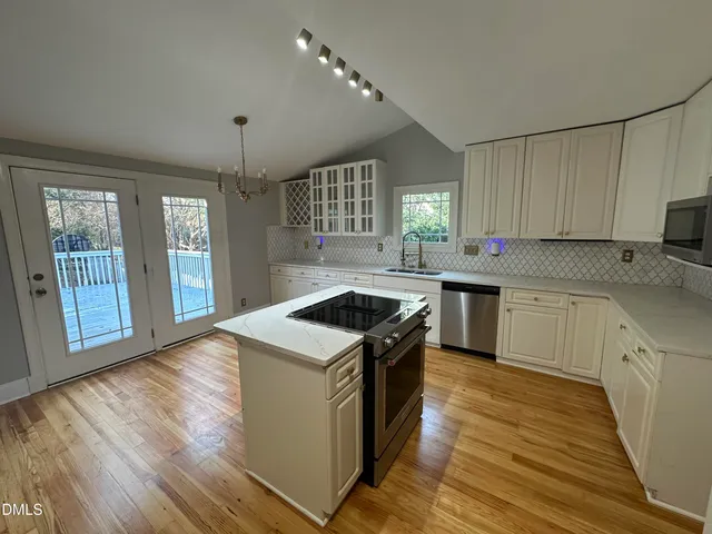 a kitchen with a sink a stove cabinets and a wooden floor
