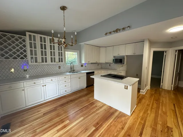 a kitchen with cabinets wooden floor and stainless steel appliances