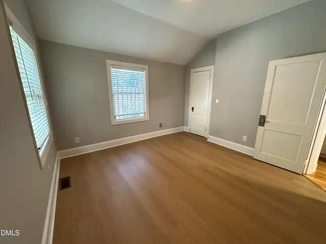 an empty room with windows and fireplace