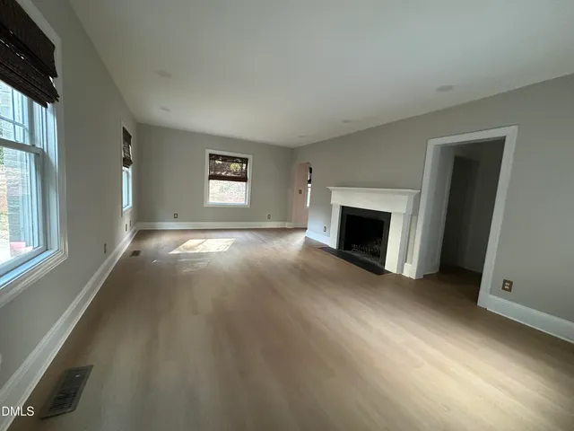 an empty room with windows and fireplace