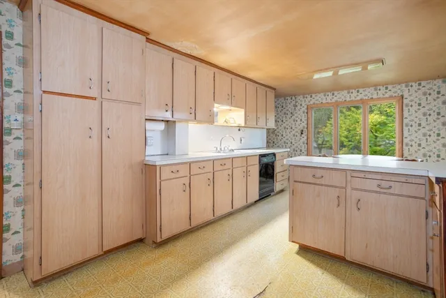 a large kitchen with stainless steel appliances granite countertop a stove a sink dishwasher and white cabinets with wooden floor