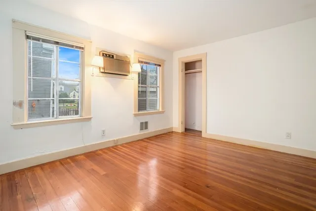 a view of an empty room with wooden floor and closet