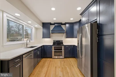 a kitchen with stainless steel appliances granite countertop a refrigerator a sink a stove and oven