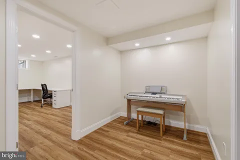 a view of a hallway with wooden floor and a bathroom
