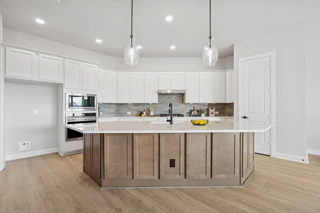 a kitchen with kitchen island a white counter top space cabinets and stainless steel appliances
