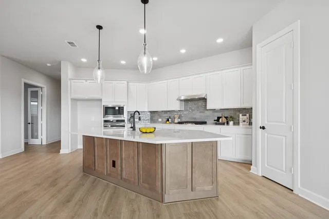 a kitchen with kitchen island stainless steel appliances a sink a refrigerator and cabinets