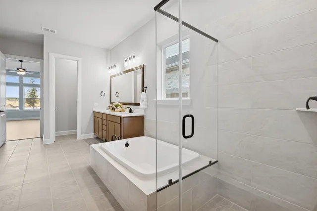 a bathroom with a tub a sink a mirror and a shower