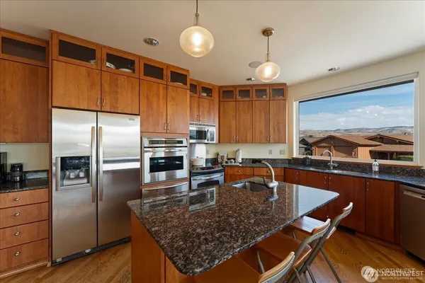 a kitchen with stainless steel appliances granite countertop a sink dishwasher stove and refrigerator with wooden floor