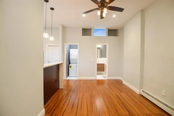 a view of a room with wooden floor a ceiling fan and windows