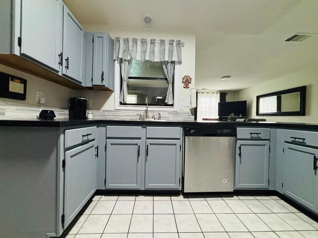 1464 Howland Boulevard Deltona, FL 32738 - Photo 9 of 55 a kitchen with white cabinets a sink a stove a microwave and cabinetry