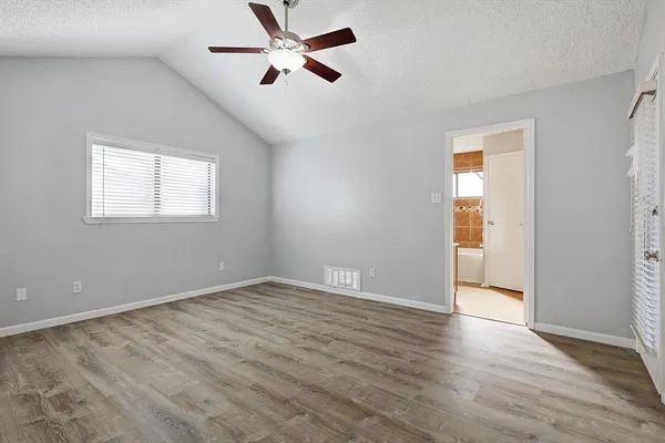 a view of empty room with wooden floor and fan