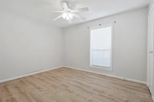 an empty room with a window and a fan