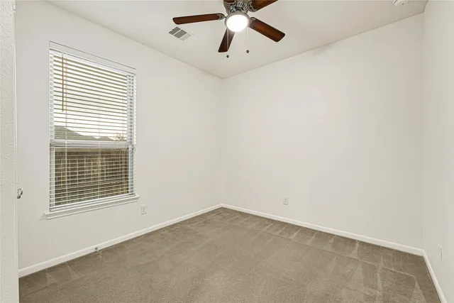 an empty room with a window and a fan