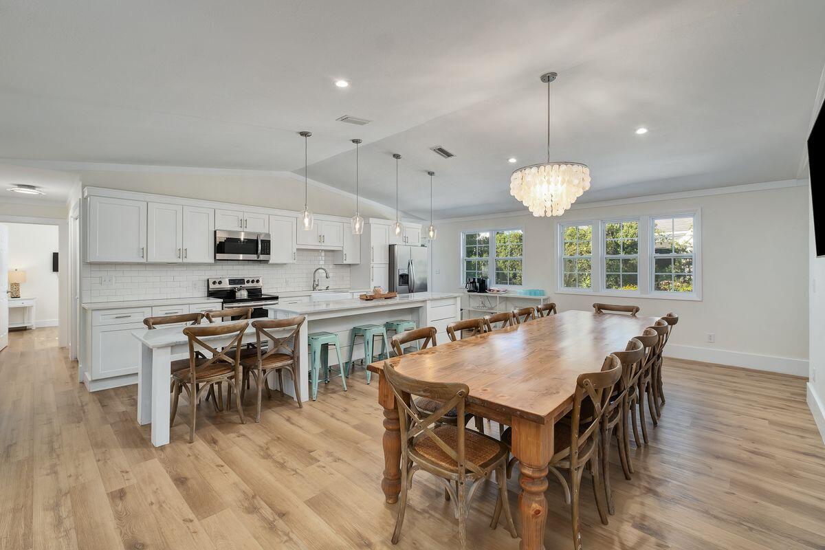 251 Dogwood Street Santa Rosa Beach, FL 32459 - Photo 12 of 51 a kitchen with stainless steel appliances granite countertop a stove a refrigerator a kitchen island a dining table and chairs with wooden floor