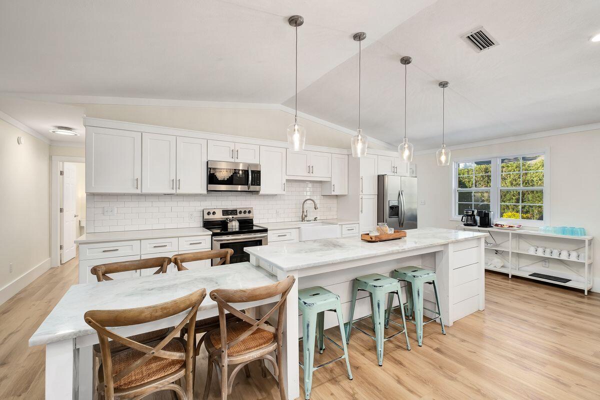 251 Dogwood Street Santa Rosa Beach, FL 32459 - Photo 16 of 51 a kitchen with stainless steel appliances a stove a sink a island with a dining table and chairs