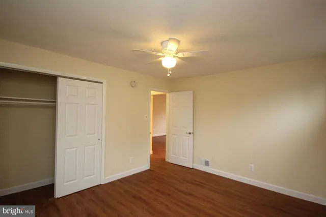 an empty room with wooden floor and a ceiling fan