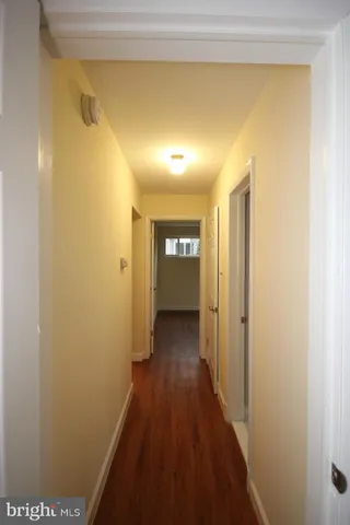 a view of a hallway with wooden floor and a bathroom