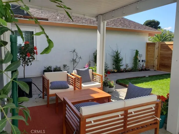 a view of a patio with table and chairs potted plants and a large tree