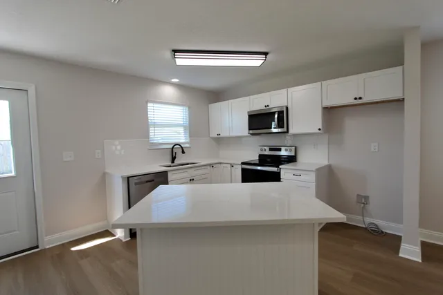 a large kitchen with cabinets stainless steel appliances and a window
