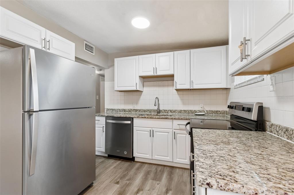 9228 82nd Way Seminole, FL 33777 - Photo 12 of 35 a kitchen with granite countertop a refrigerator stove top oven and sink