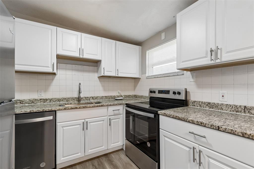 9228 82nd Way Seminole, FL 33777 - Photo 13 of 35 a kitchen with granite countertop stainless steel appliances white cabinets granite counter tops and a wooden floors