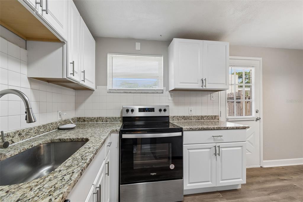 9228 82nd Way Seminole, FL 33777 - Photo 14 of 35 a kitchen with granite countertop a stove sink and cabinets