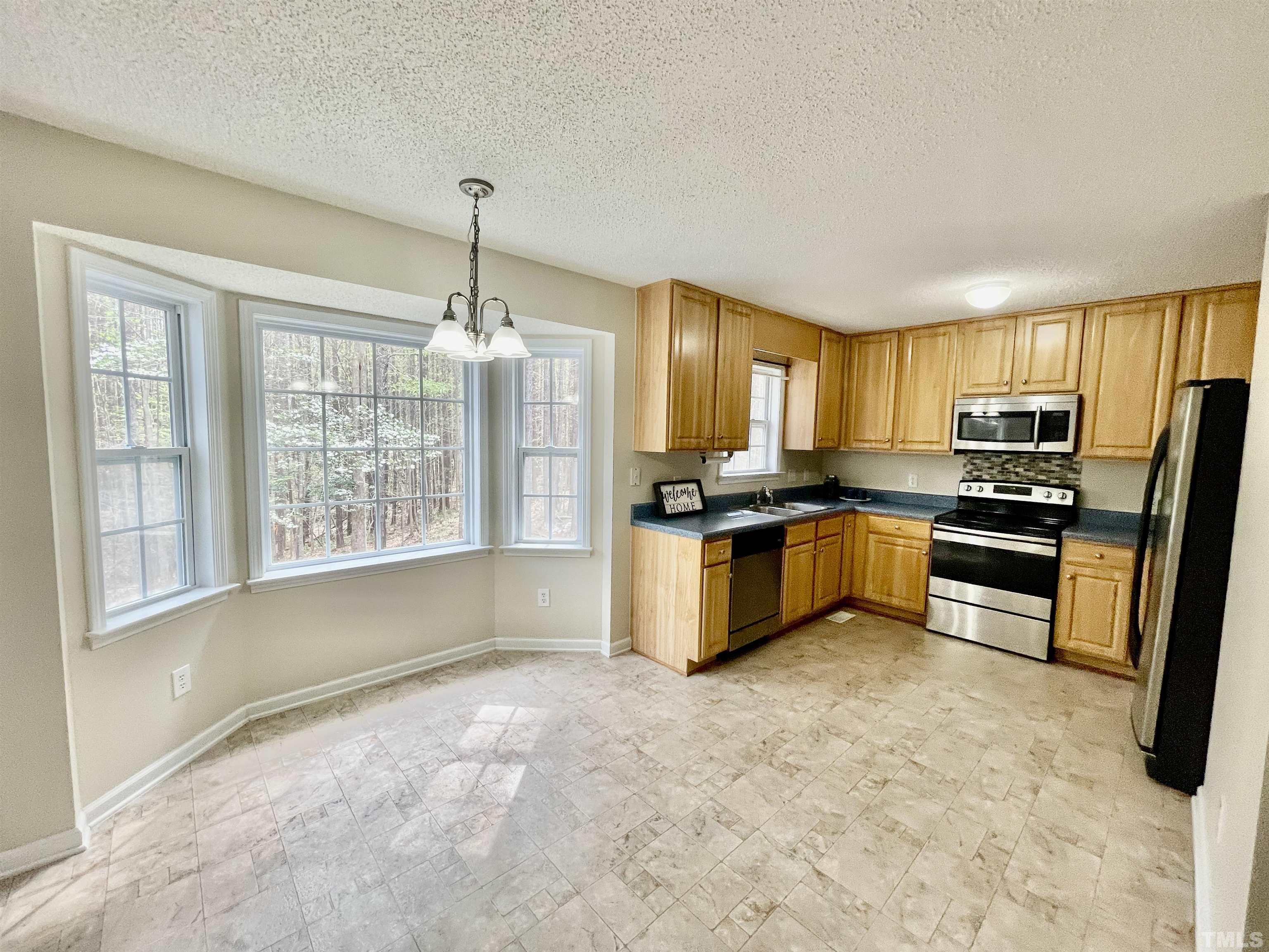 6105 Ruddington Court Willow Spring, NC 27592 - Photo 4 of 18 a kitchen with kitchen island a counter top space appliances and a window