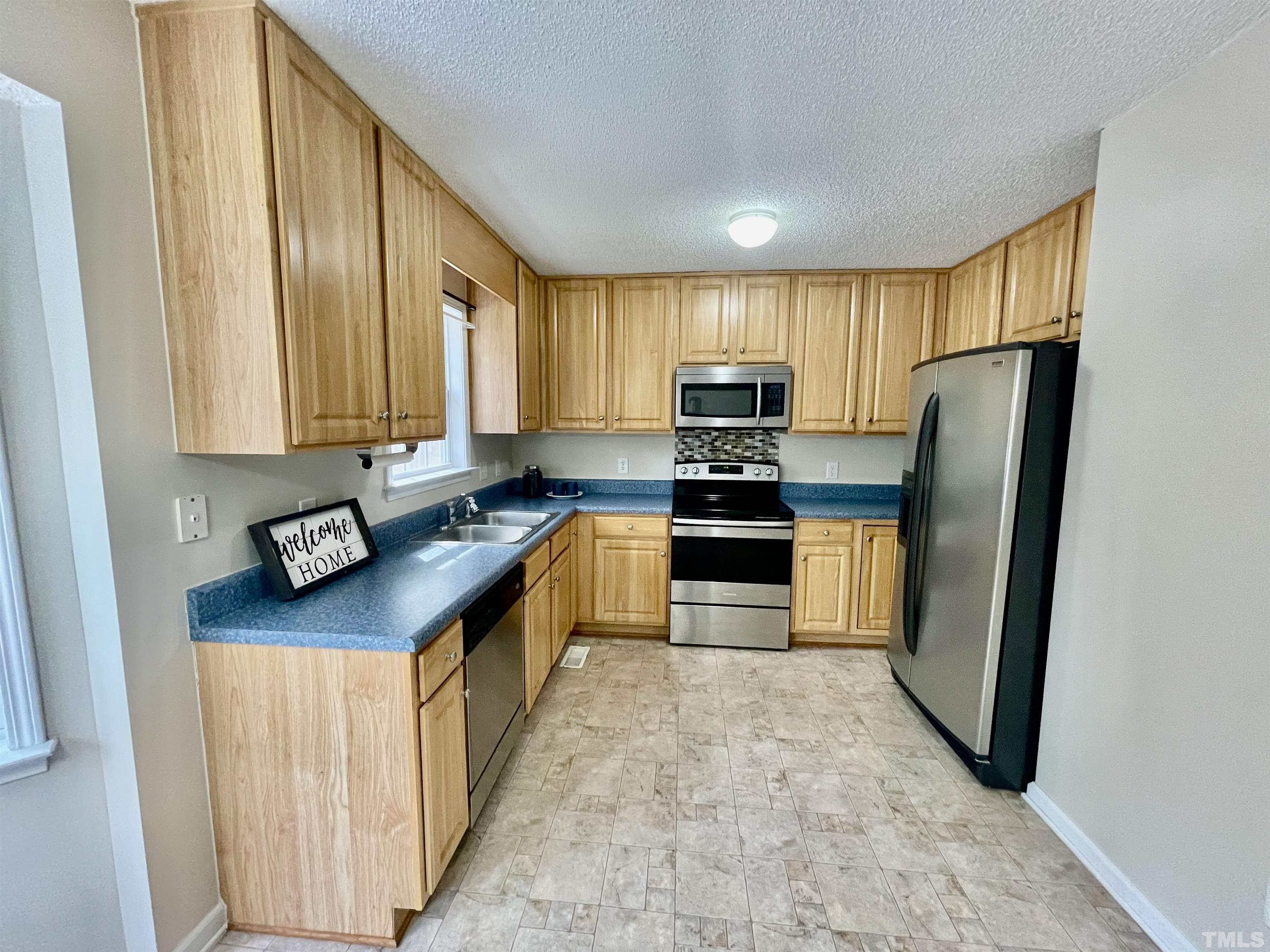 6105 Ruddington Court Willow Spring, NC 27592 - Photo 5 of 18 a kitchen with stainless steel appliances granite countertop a refrigerator a stove and a sink