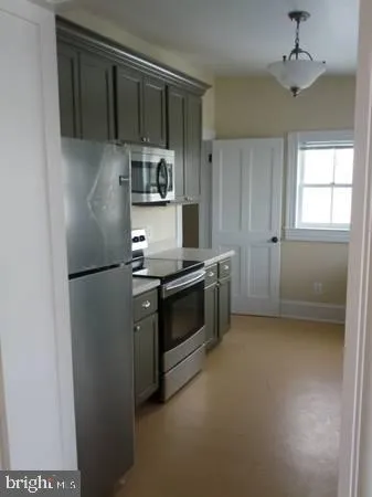 a kitchen with stainless steel appliances a refrigerator a stove a sink and white cabinets