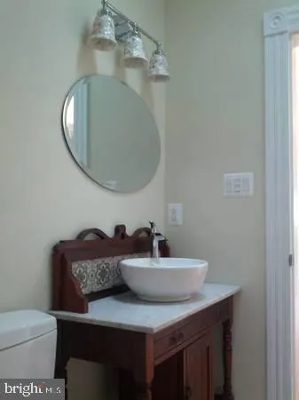 a bathroom with a granite countertop toilet a sink and mirror