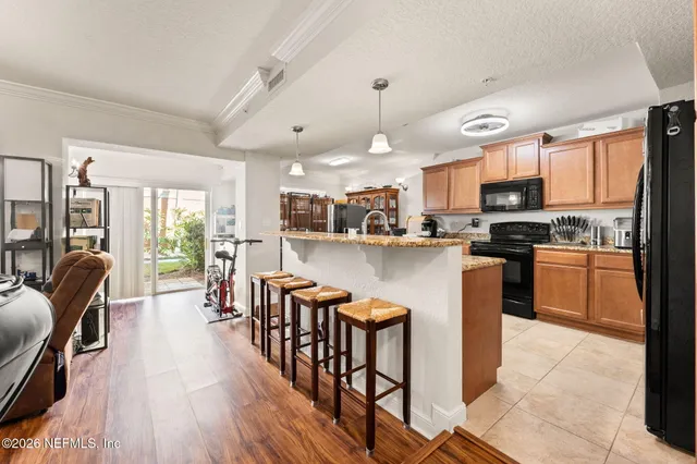 a kitchen with stainless steel appliances granite countertop a refrigerator a stove top oven a sink dishwasher a dining table and chairs with wooden floor